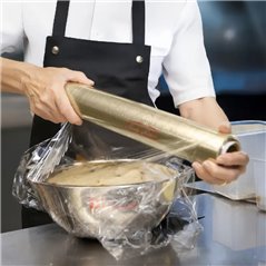Cocinero tapando un bowl de acero con film de polietileno sobre la mesada