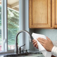 Toallas intercaladas blancas para secado de manos en cocina institucional.