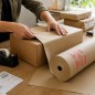 Persona envolviendo un paquete mediano con papel kraft de 60 cm en un mostrador de packing - Papelera Damián Persona envolviendo un paquete mediano con papel kraft de 60 cm en un mostrador de packing - Papelera Damián