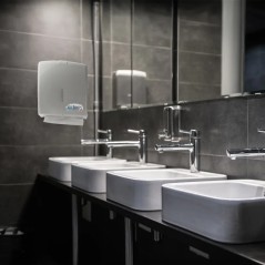 Dispenser de toallas intercaladas montado en el baño de una institución.