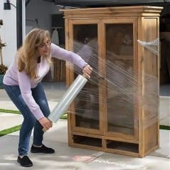 Mujer envolviendo un ropero de madera con film stretch con mango, de pie y sin ayuda