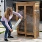 Mujer envolviendo un ropero de madera con film stretch con mango, de pie y sin ayuda