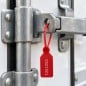Precinto cola de ratón rojo numerado cerrando la traba de la puerta de un camión