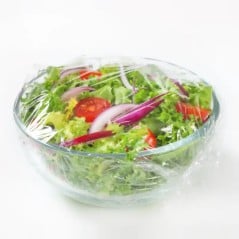 Bowl de vidrio con ensalada tapado con papel film para guardarlo en la heladera